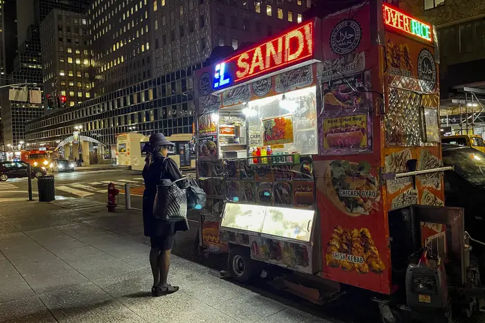 someone orders food from a cart at night